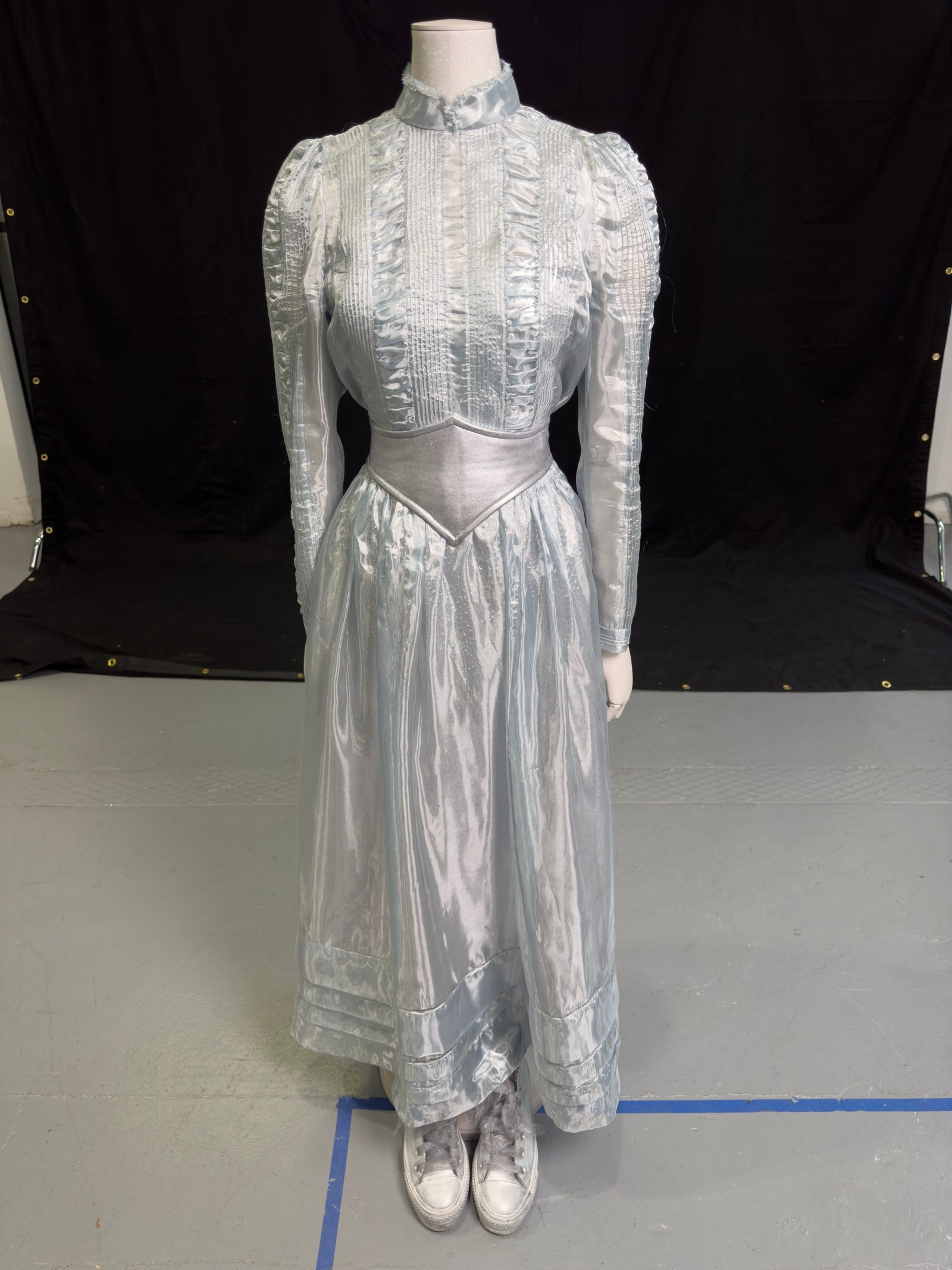 Imagens da esquerda para a direita: Um vestido usado por Jenna Ortega, um fato usado por Michael Keaton, e um vestido usado por Monica Bellucci.