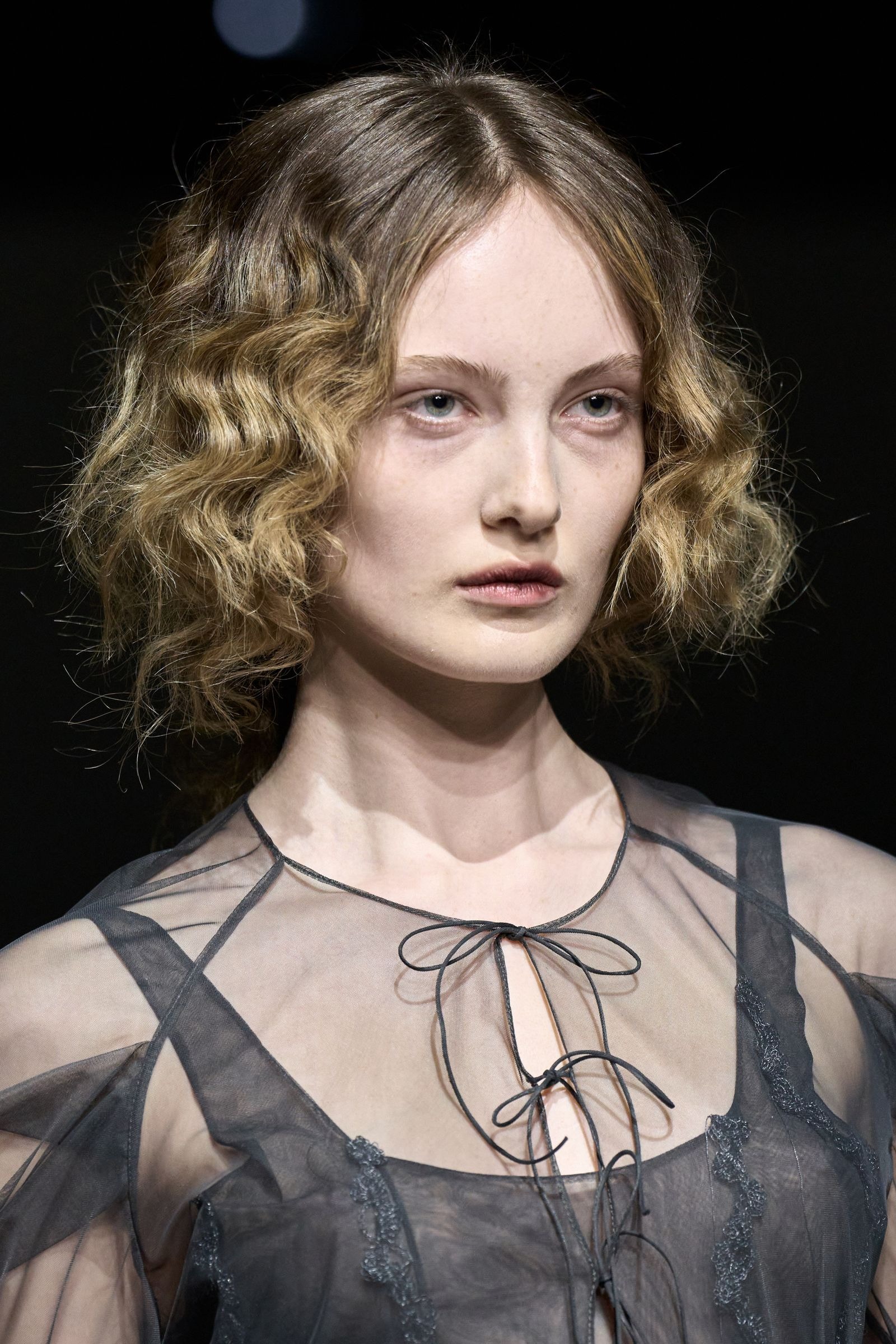 Modelo no desfile da Dujancourt, com um corte de cabelo bob encaracolado.