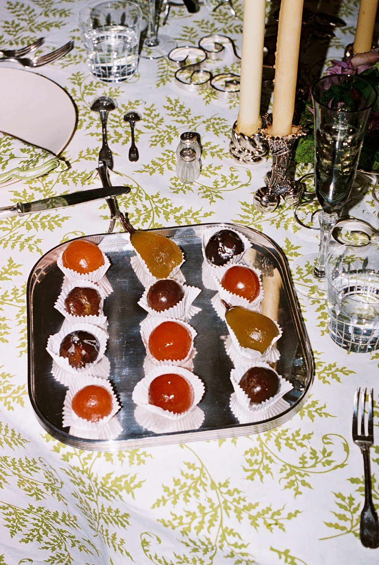 “O que interessa é a forma como o ambiente evolui ao longo da noite,” diz Newman. Os frutos glacé da Fortnum and Mason dão um toque extravagante à decoração de mesa. “O que interessa é a forma como o ambiente evolui ao longo da noite,” diz Newman. Os frutos glacé da Fortnum and Mason dão um toque extravagante à decoração de mesa.